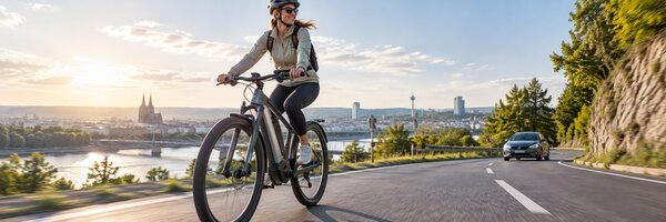 E-Bike auf einer Straße mit Auto und Stadt im Hintergrund – Mobilität, Fahrrad und Verkehr